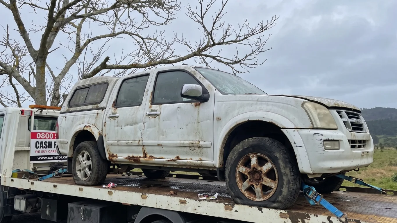 Rusted white pickup truck on a tow truck flatbed for Car Wreckers Dunedin.